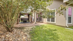 Une maison dotée d’un patio, d’un espace extérieur couvert aménagé en salon et d’une pelouse.