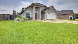 Une maison de plain-pied avec un garage, une cour avant avec une pelouse et des parterres de fleurs, et une clôture en bois.