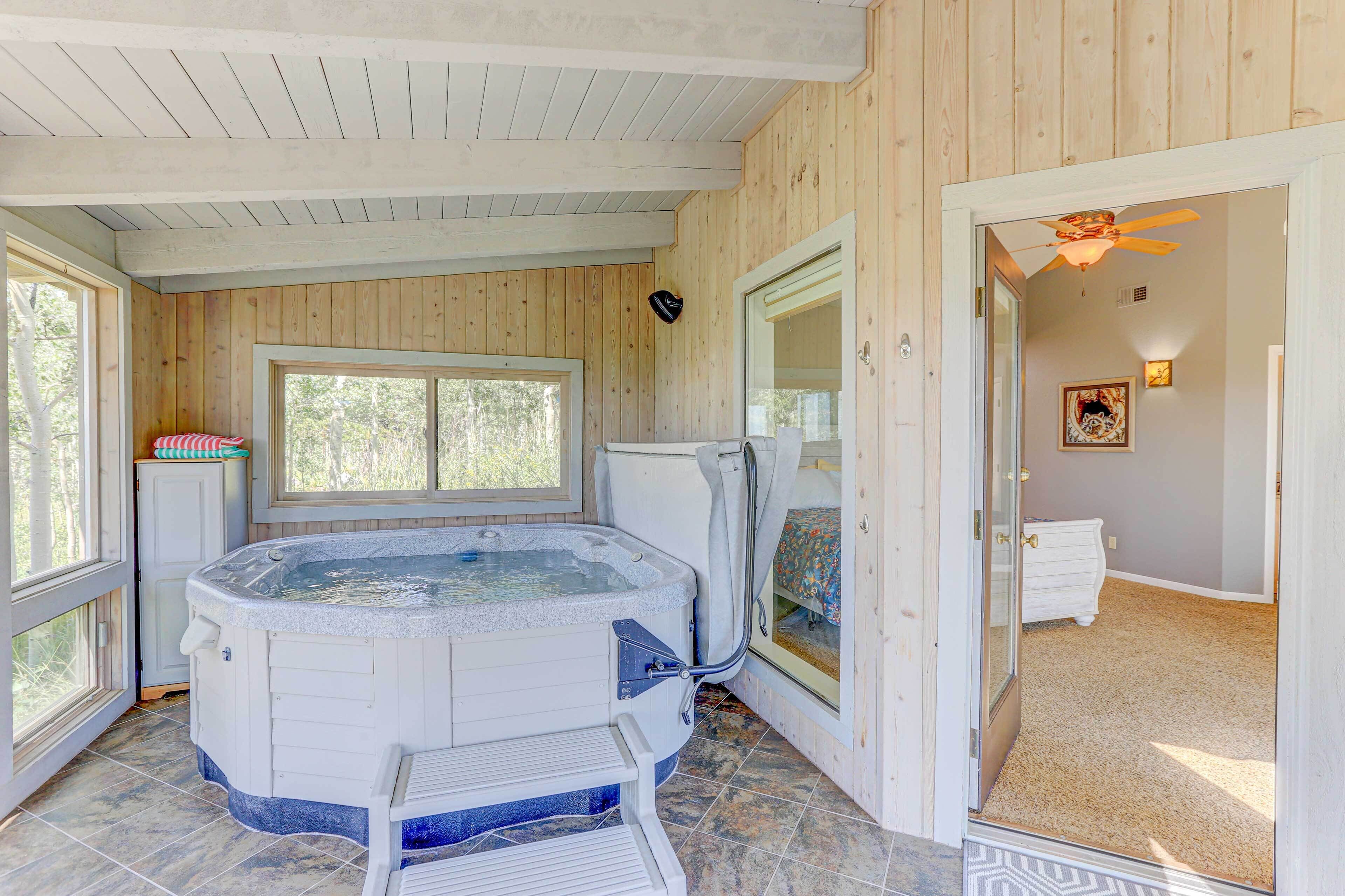 Un interior de madera con una bañera de hidromasaje, una ventana y una puerta que da a otra habitación.