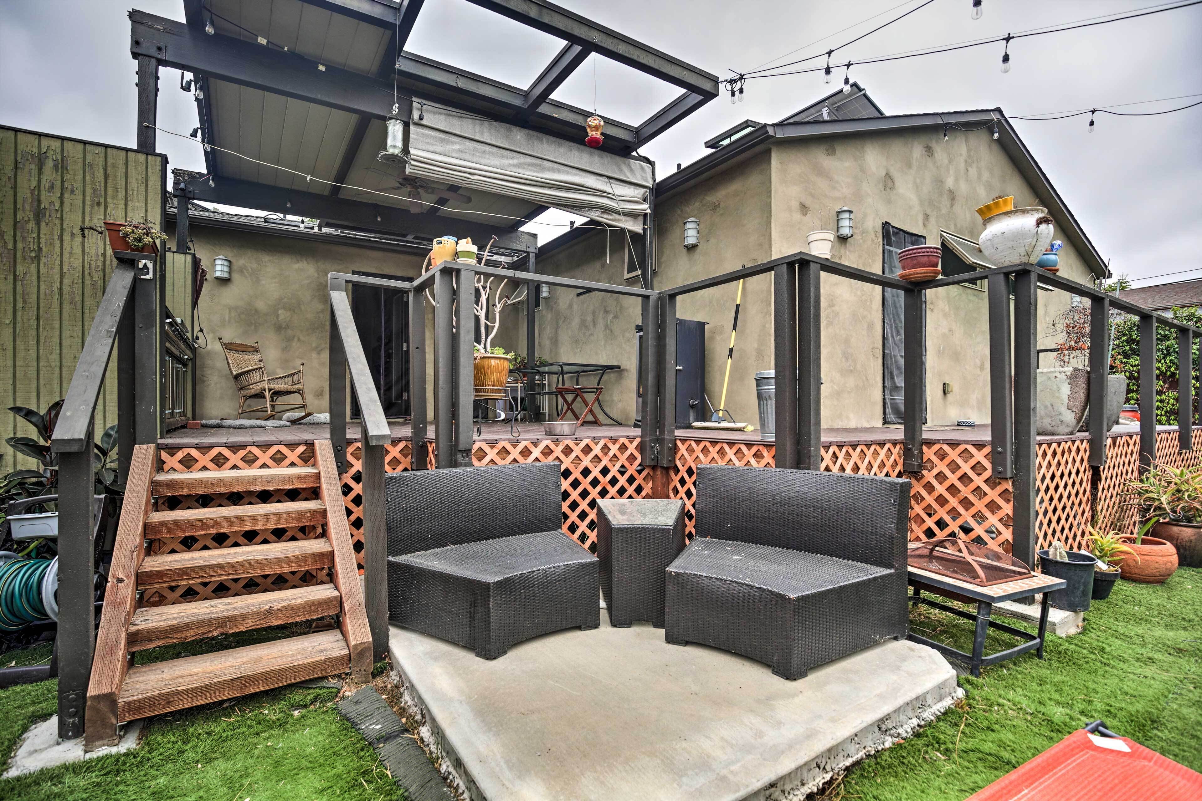 Een patio met buitenmeubilair, een houten trap en een overdekte zithoek.