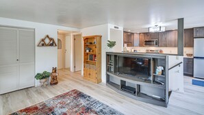 Une cuisine moderne avec des meubles en bois, un four à micro-ondes encastré et un grand téléviseur.