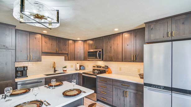 Une cuisine moderne avec des meubles en bois foncé, des appareils électroménagers en acier inoxydable et un îlot central en marbre.