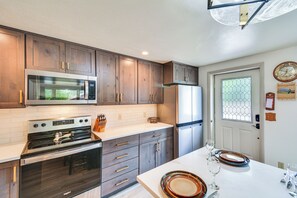 Una cocina moderna con armarios de madera, electrodomésticos de acero inoxidable y encimera blanca.