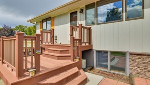 Une maison à deux étages avec une terrasse en bois et un mur en pierre.