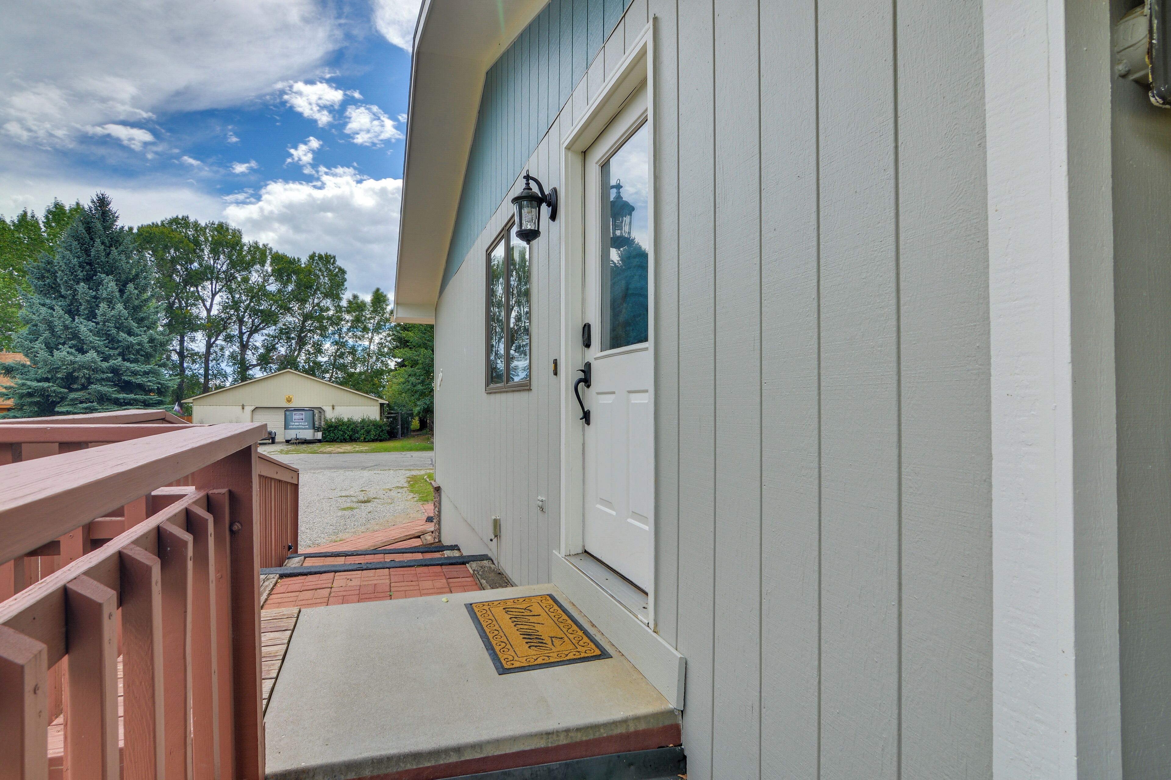 A white building with a porch, a mailbox, and a door with a window.