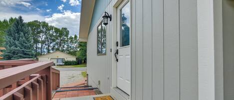 A white building with a porch, a mailbox, and a door with a window.