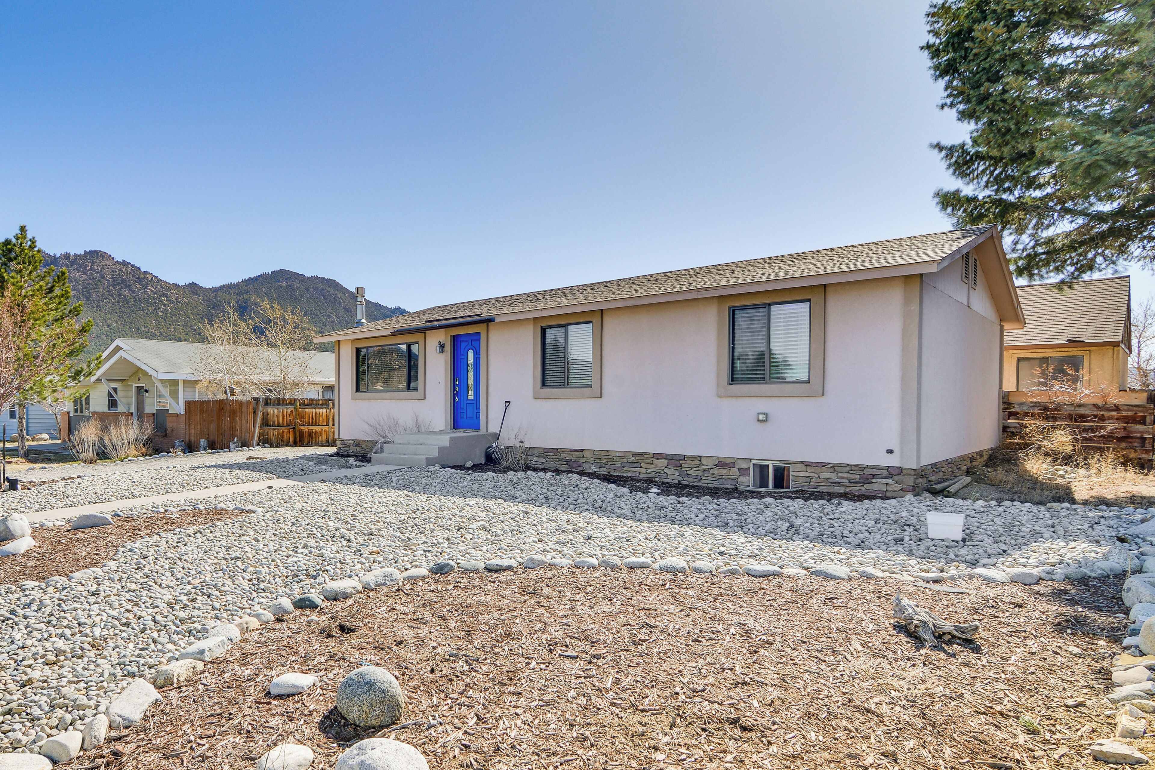 Una casa de un piso con puerta azul, paredes exteriores color beige y cimientos de piedra.
