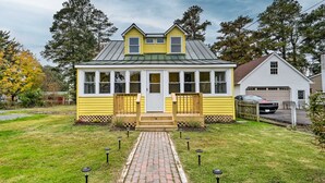 A yellow house with a front porch, a garage, and a paved driveway. - Updated North Beach Cottage: Pet Friendly! (North Beach)