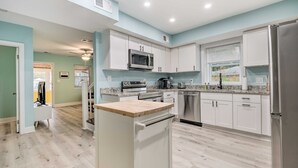 A modern kitchen with white cabinets, stainless steel appliances, and a wooden countertop. - Updated North Beach Cottage: Pet Friendly! (North Beach)