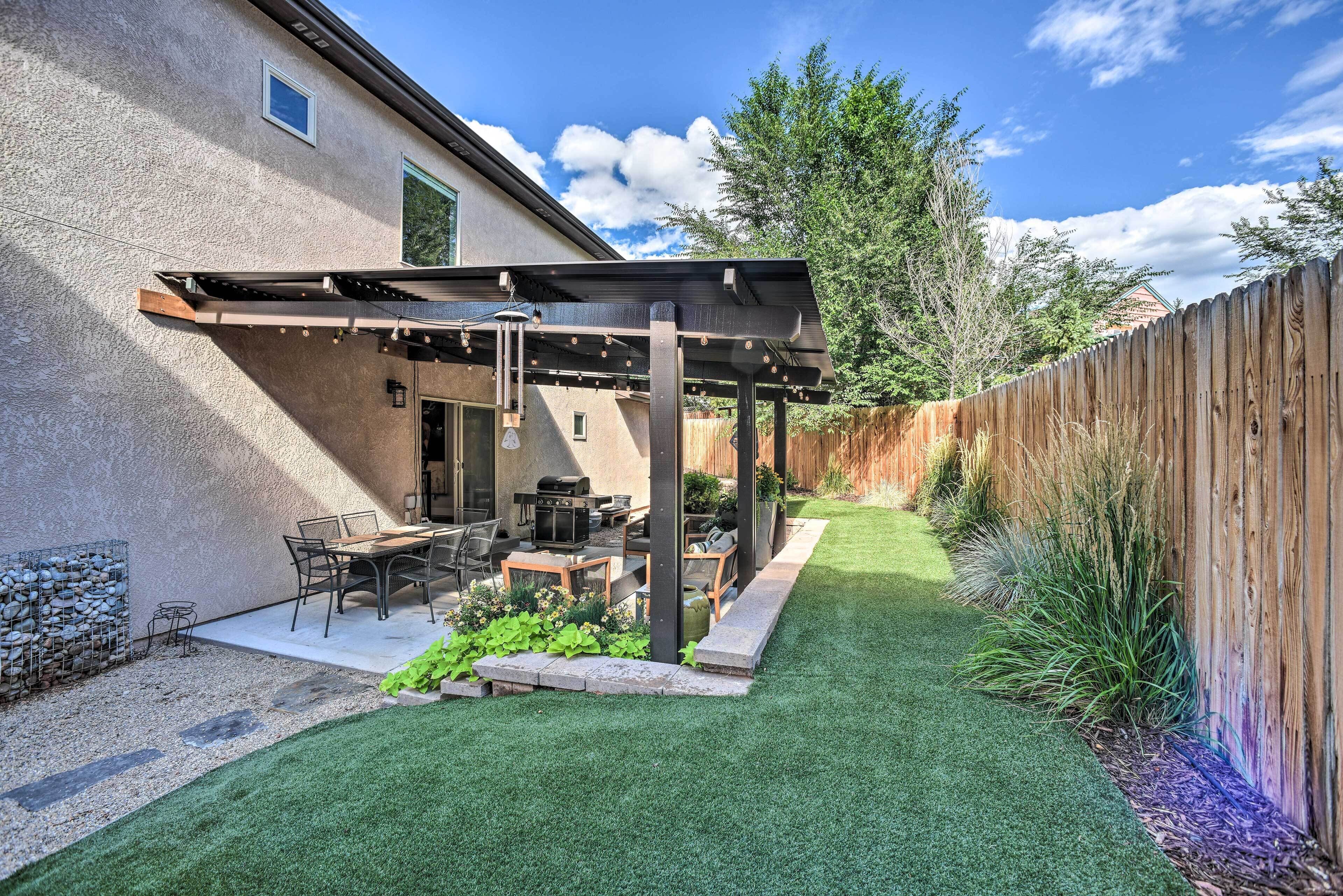 A backyard with a pergola, outdoor furniture, and a well-maintained lawn.