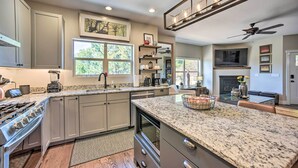 A modern kitchen with granite countertops, a built-in oven, and a large island. - Modern Home w/ Patio Near Garden of the Gods! (Colorado Springs)