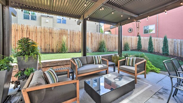 An outdoor patio area with a covered seating arrangement, including a sofa, chairs, and a coffee table. - Modern Home w/ Patio Near Garden of the Gods! (Colorado Springs)