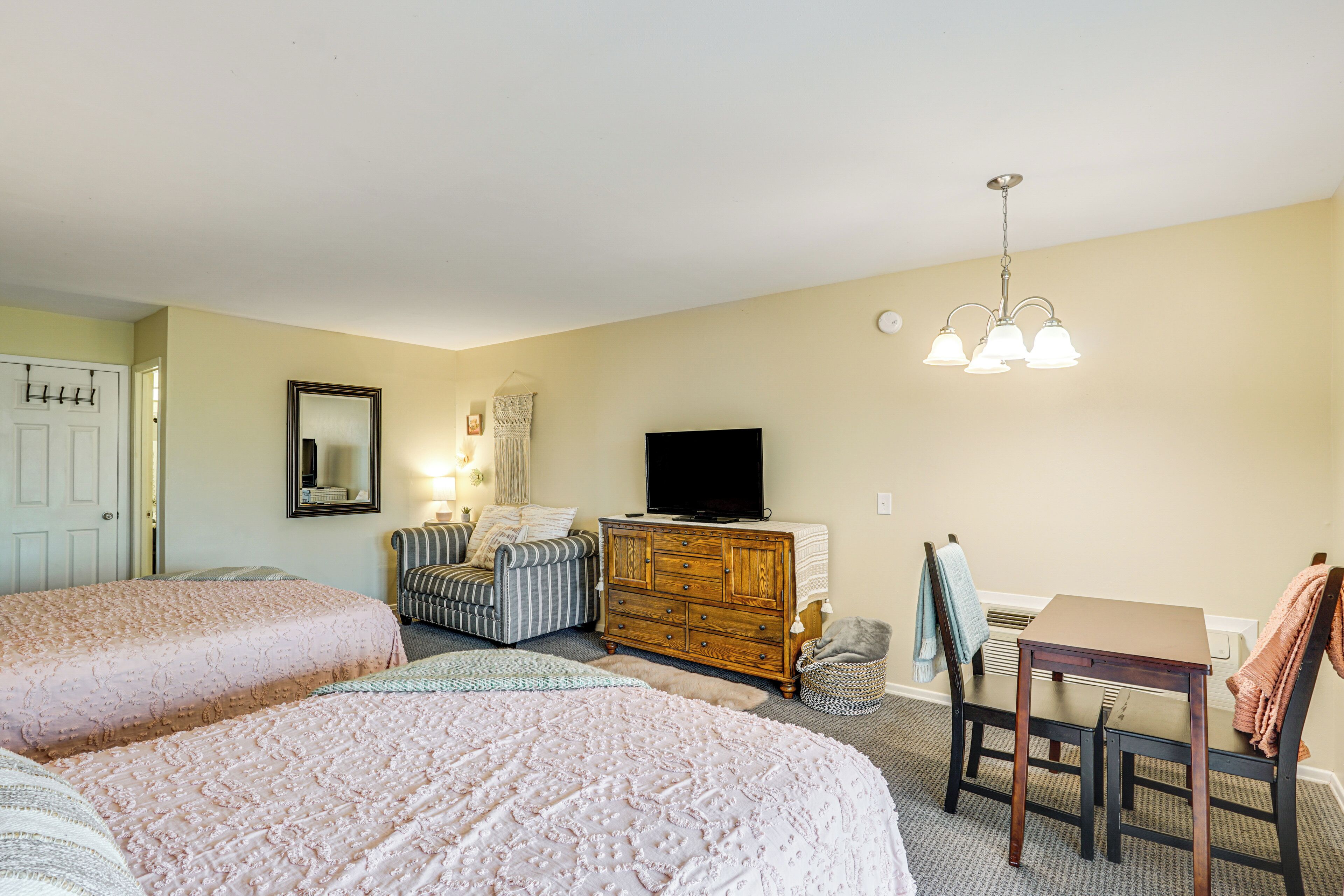 A bedroom with two beds, a dresser, a TV, a chair, and a table.