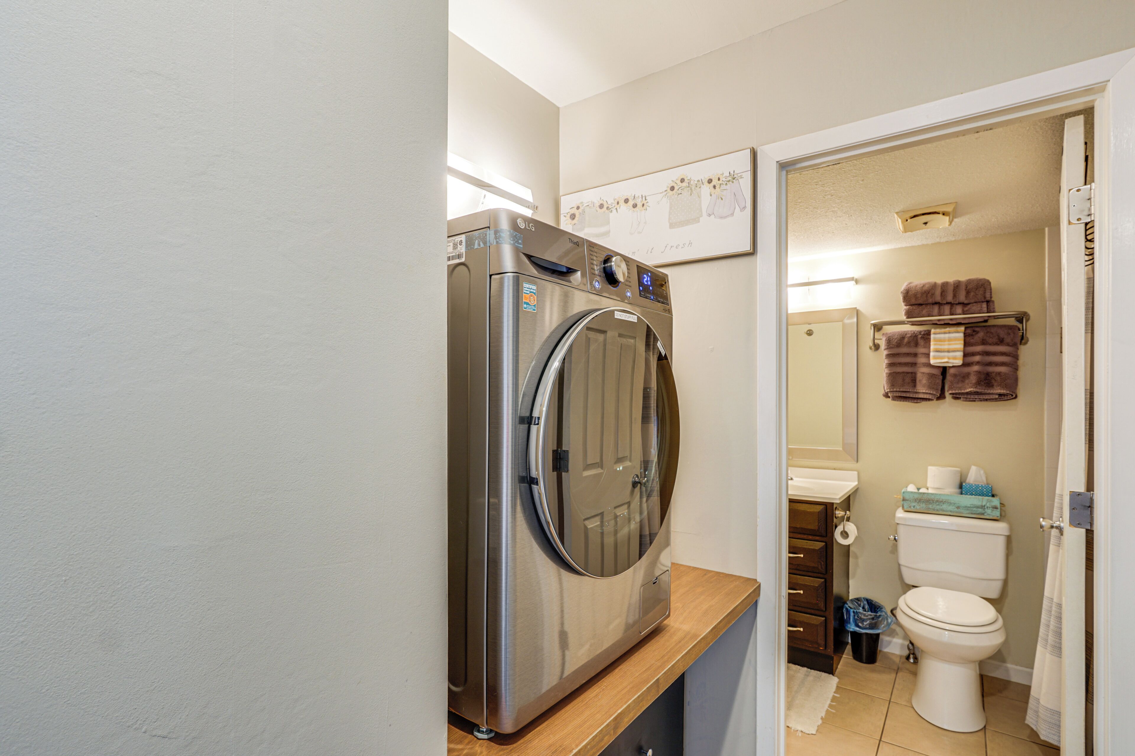 Ein kleiner Waschraum mit einer Frontlader-Waschmaschine, einer Toilette und einem Waschbecken.