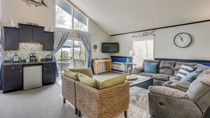 Ein großzügiger Wohnbereich mit Küche, großem Fenster, Flachbildfernseher und bequemer Couch.