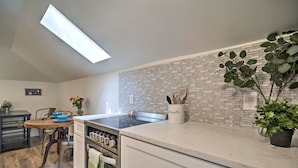 A modern kitchen with a brick backsplash, a skylight, and a dining area with a table and chairs. - Dtwn Golden Apt < 9 Mi to Red Rocks Amphitheater! (Golden)