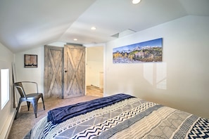 A bedroom with a bed, a chair, a wooden door, and a painting on the wall. - Dtwn Golden Apt < 9 Mi to Red Rocks Amphitheater! (Golden)