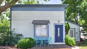 A small, single-story building with a blue door and window, a small porch with a table and chairs, and a well-maintained garden. - Dtwn Golden Apt < 9 Mi to Red Rocks Amphitheater! (Golden)