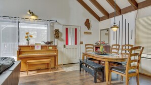 Ein gemütliches Zimmer mit einem Klavier, einem Holzespeisetisch und Stühlen.