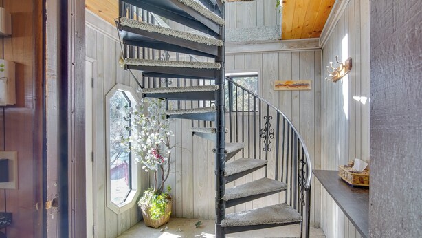 Eine Wendeltreppe mit Holzvertäfelung und Metallgeländern, die zu einer oberen Etage führt.