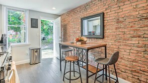 A kitchen with a brick wall, a window, and a sink.