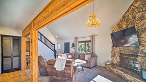 Ein gemütliches Wohnzimmer mit Kamin aus Stein, Holzboden und einem an der Wand befestigten Fernseher.