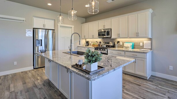 A modern kitchen with white cabinets, stainless steel appliances, and a granite countertop.