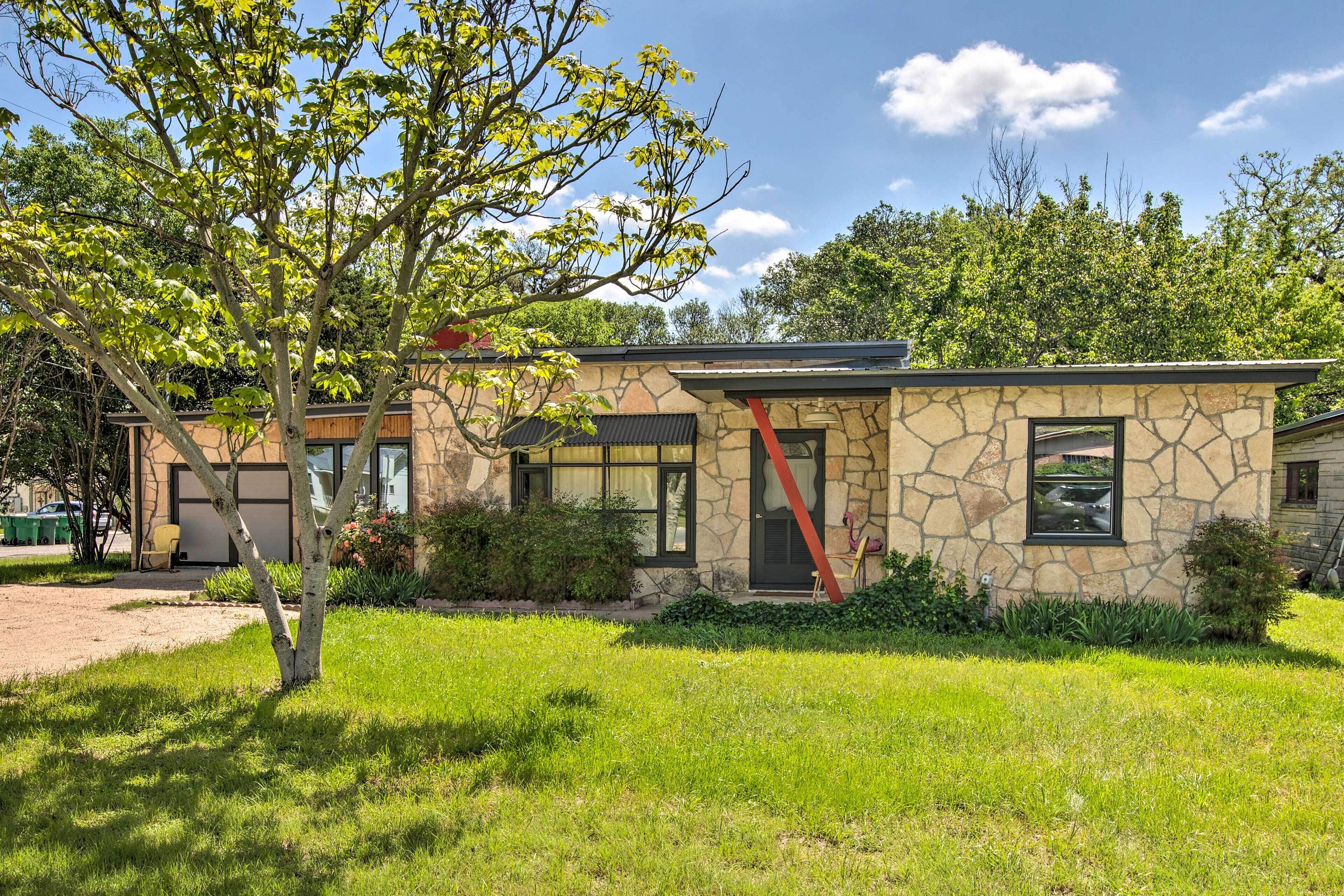 Una casa in pietra dal design moderno, con un cortile e un albero.