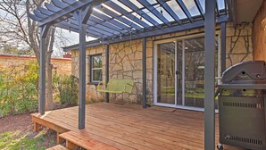 Un patio techado con bancos de madera, una parrilla y una pérgola.
