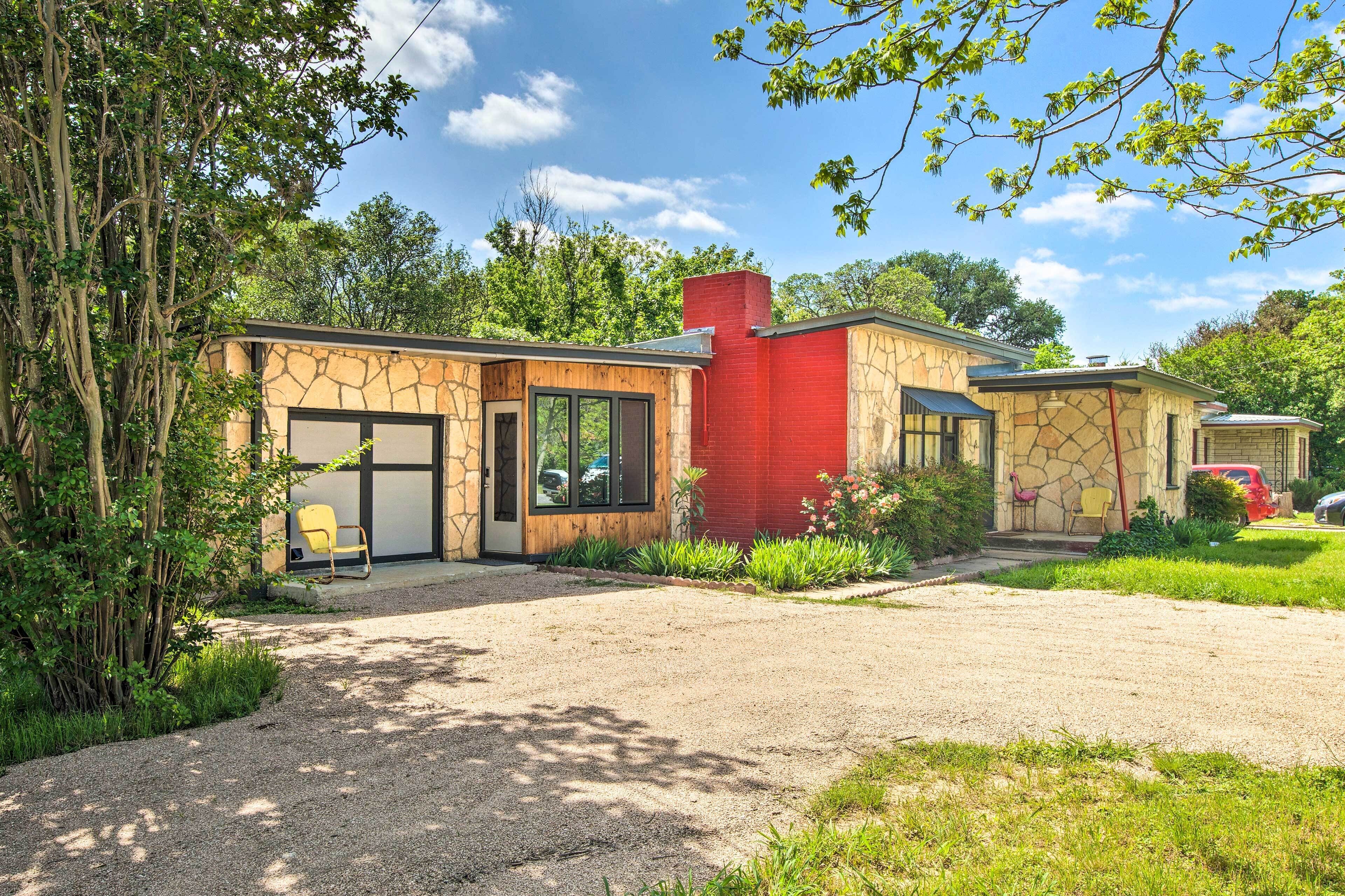Une maison moderne avec une façade en pierre, une cheminée en briques rouges et une allée gravillonnée.