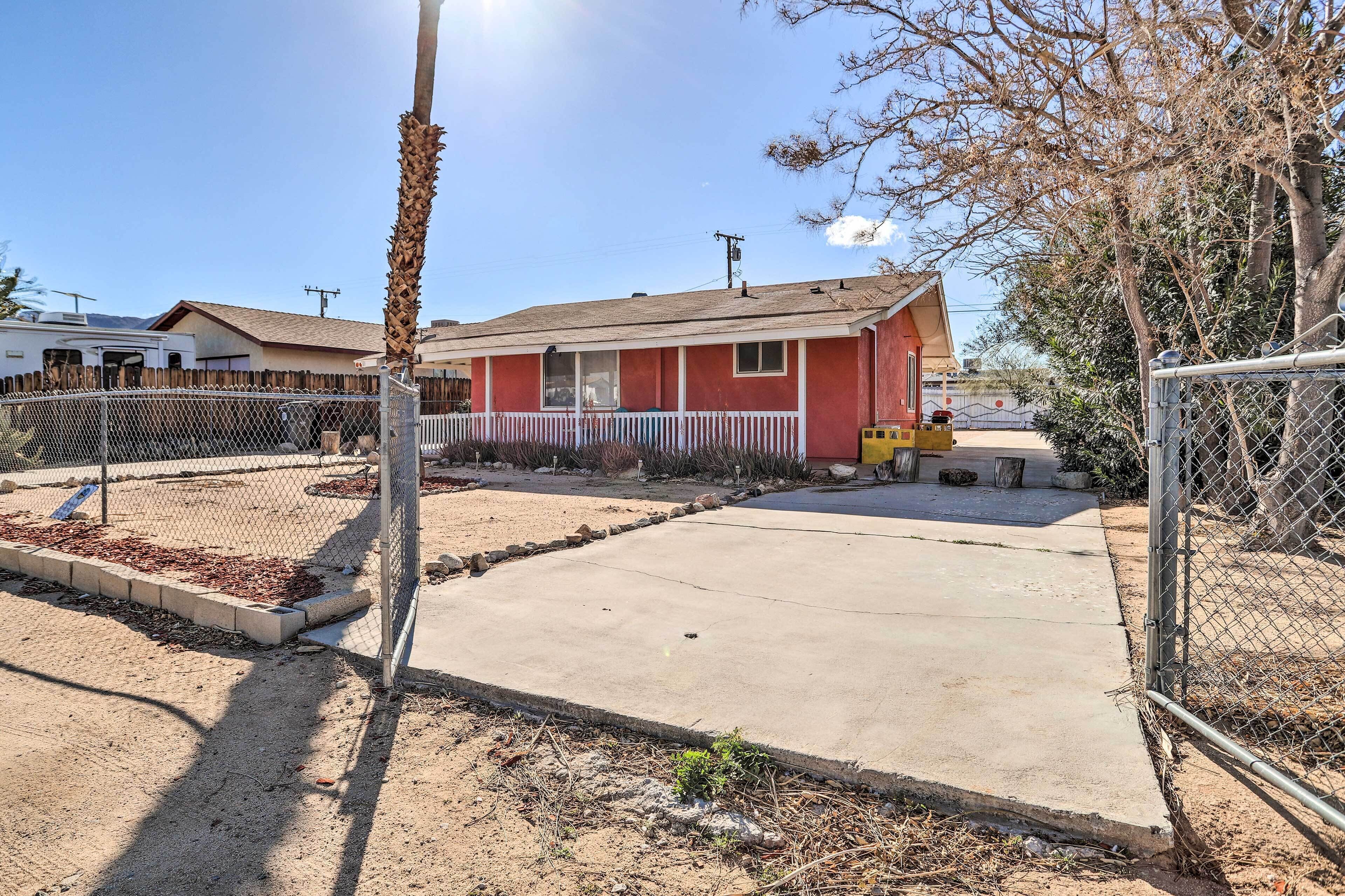 A red house with a fenced yard and a concrete driveway.