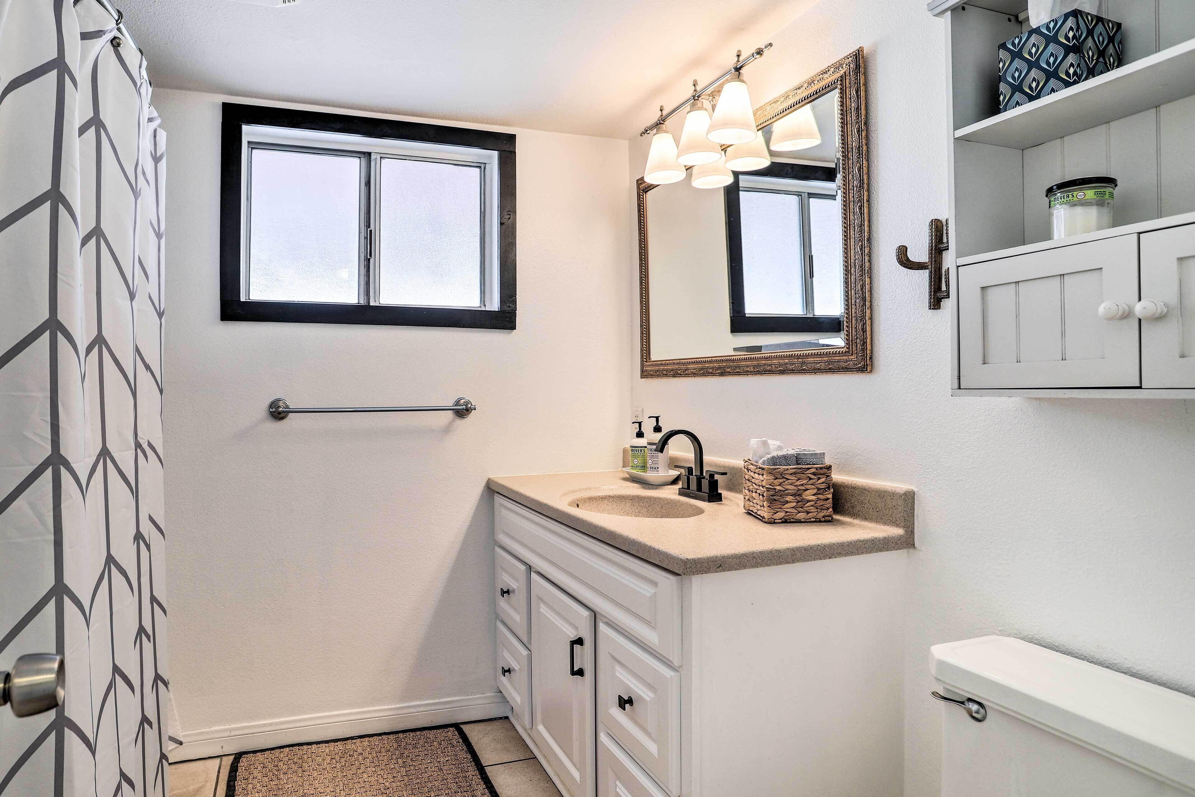 Ein Badezimmer mit Fenster, Waschbecken, Spiegel und Toilette.
