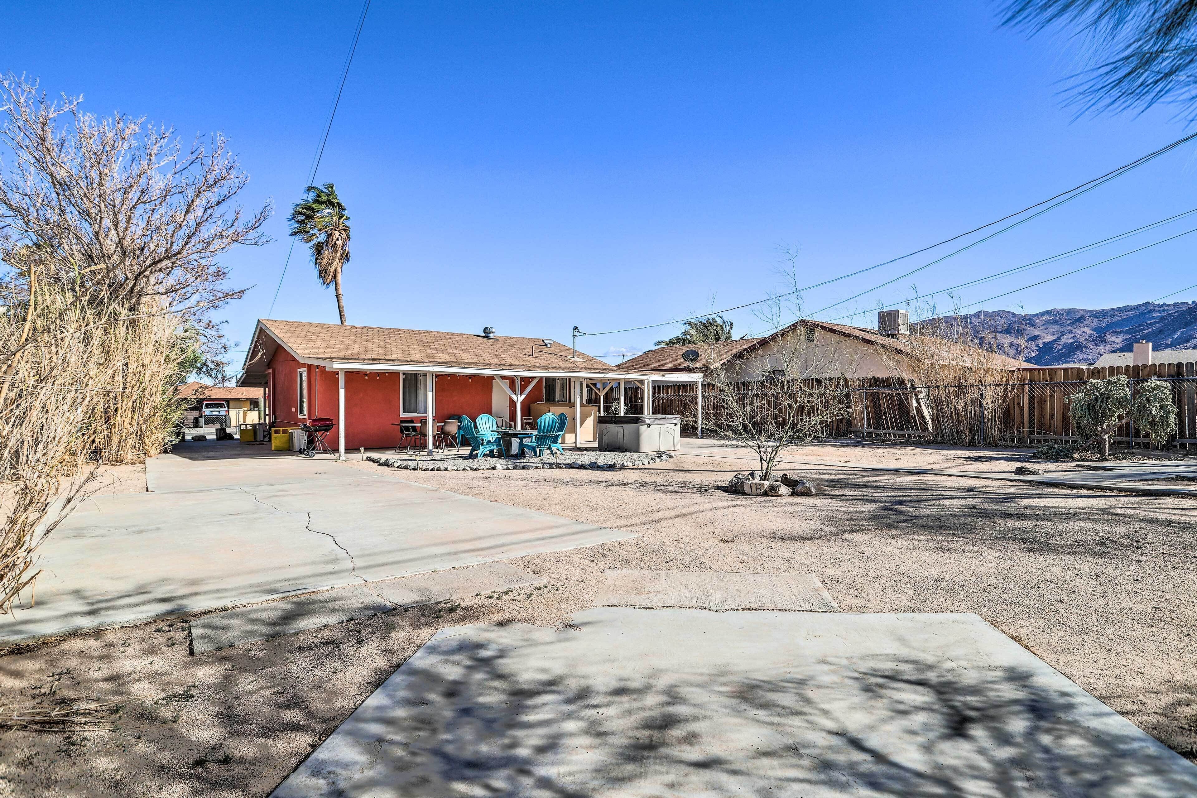 A residential area with a red house, a covered patio, and a fenced yard.