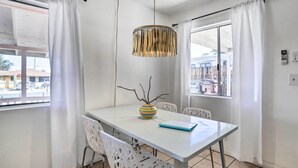 A modern dining area with a white table, chairs, and a hanging light fixture.