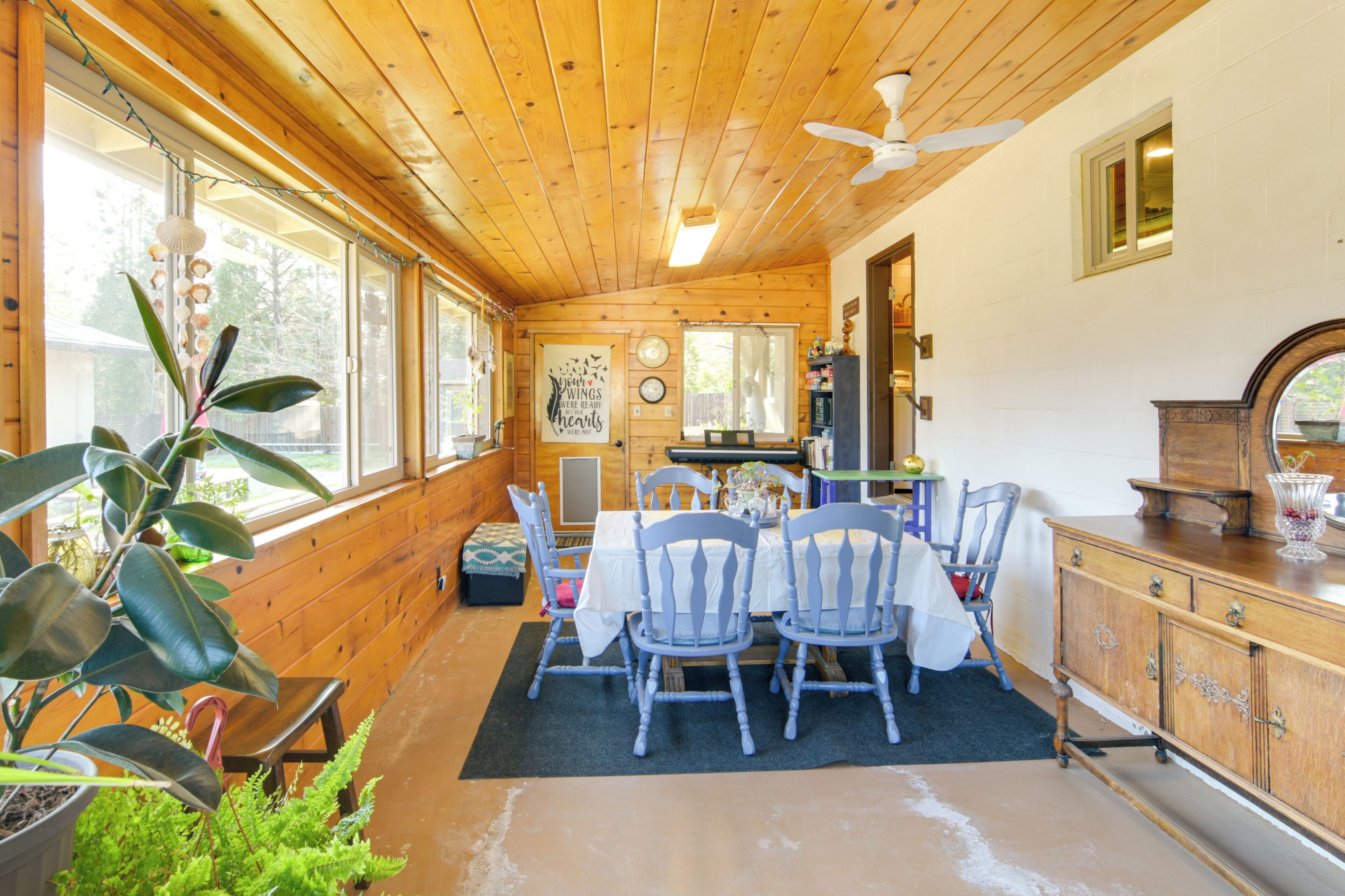 A wooden cabin interior with a dining area, wooden walls, and large windows.