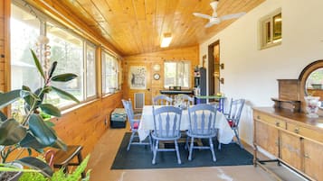 A wooden cabin interior with a dining area, wooden walls, and large windows.