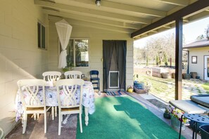 A covered patio with a table and chairs, a green artificial turf, and a view of the backyard. - Quiet Challenge-brownsville Home Near Collins Lake (Brownsville)