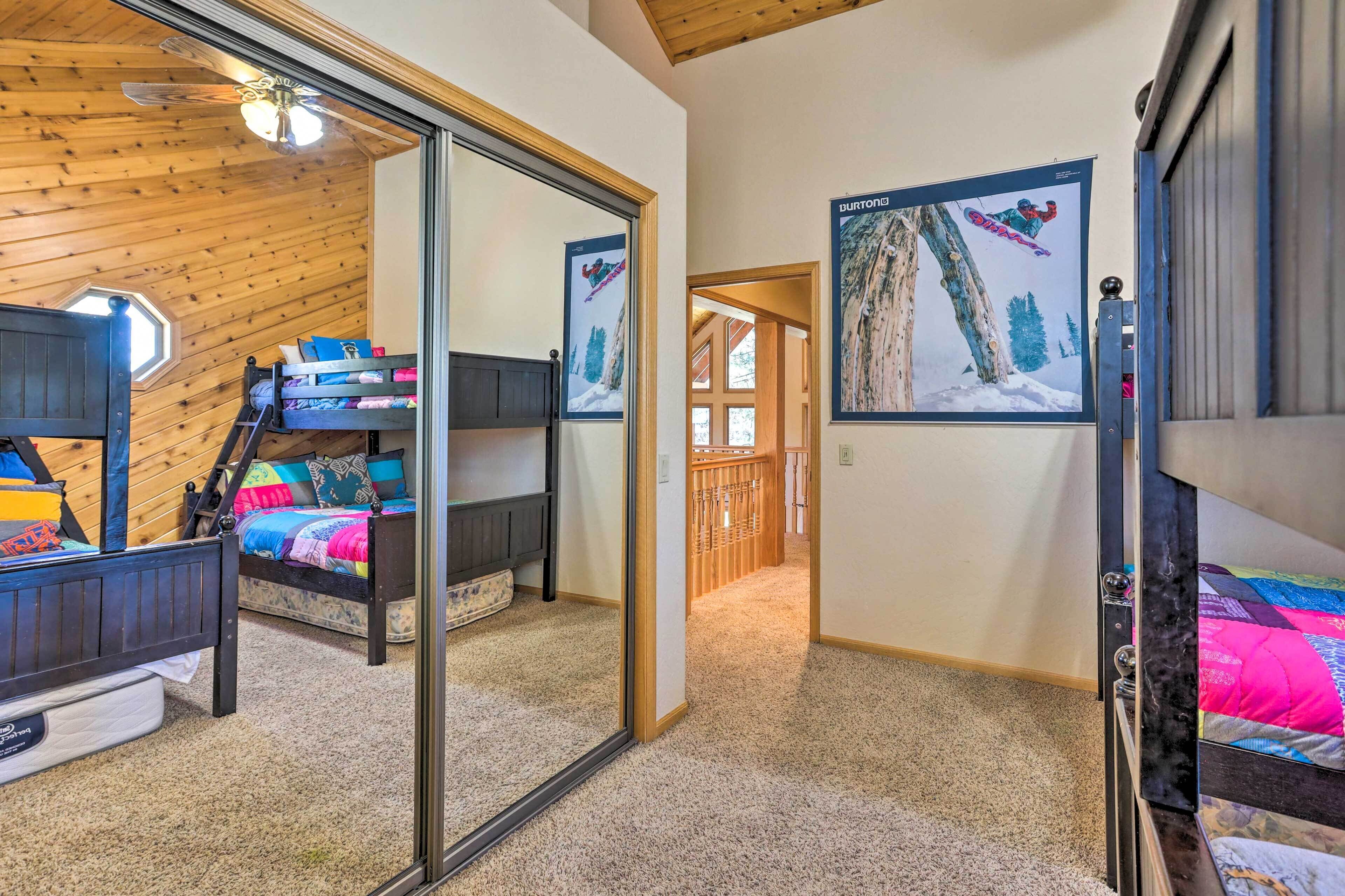 Een slaapkamer met stapelbedden, een houten plafond en een grote spiegel.