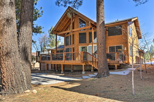 A large wooden cabin with multiple windows, a deck, and a staircase leading to the main entrance. - Walk to Ski Lift: Gem w/ Hot Tub in Big Bear Lake (Big Bear Lake)
