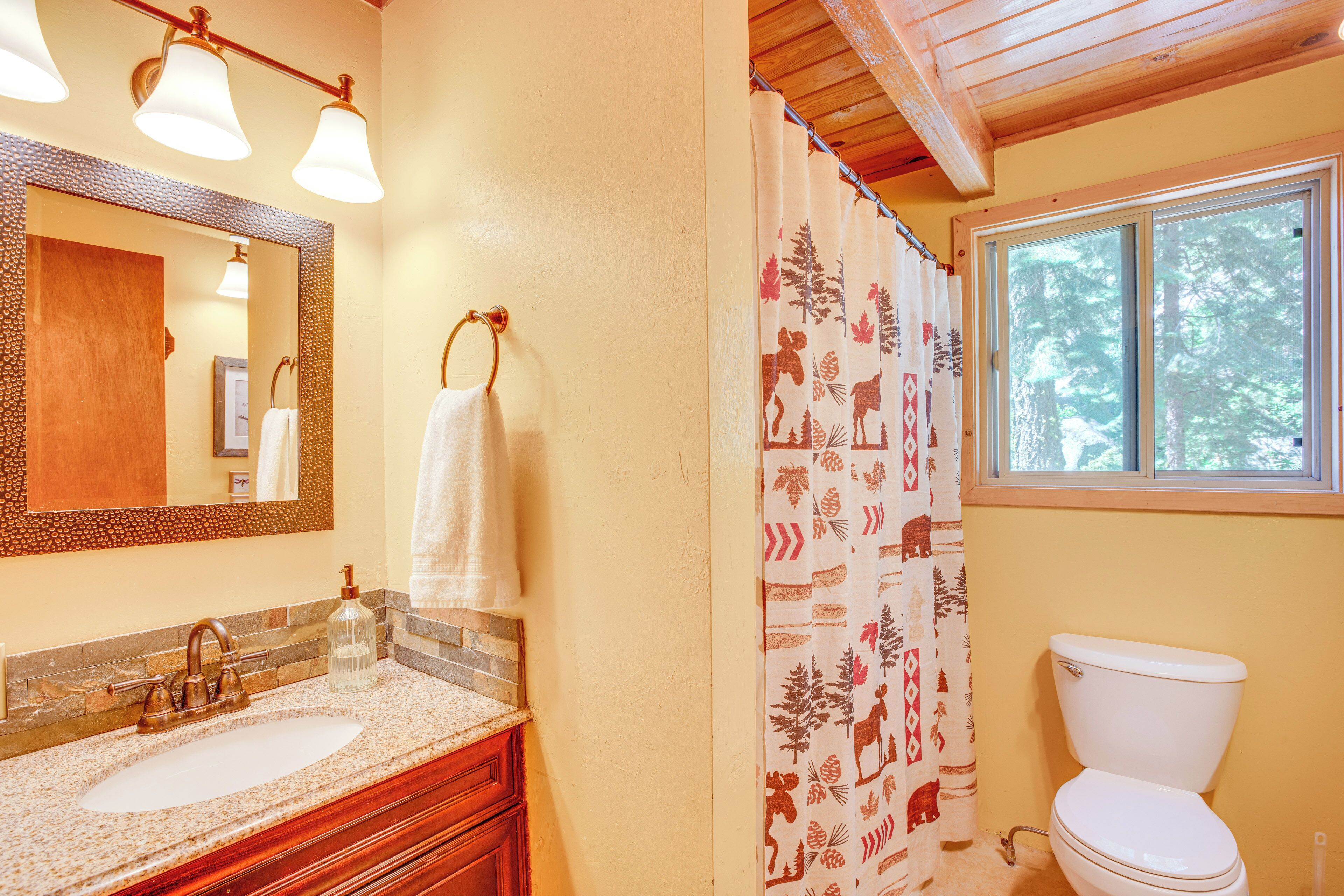 Une salle de bain avec un meuble-lavabo en bois, un lavabo blanc, un miroir et des toilettes.