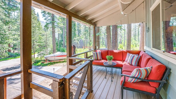 A covered porch with a red sofa, a small table, and a potted plant. - 10 Mi to Ski Slopes: South Lake Tahoe Home (South Lake Tahoe)