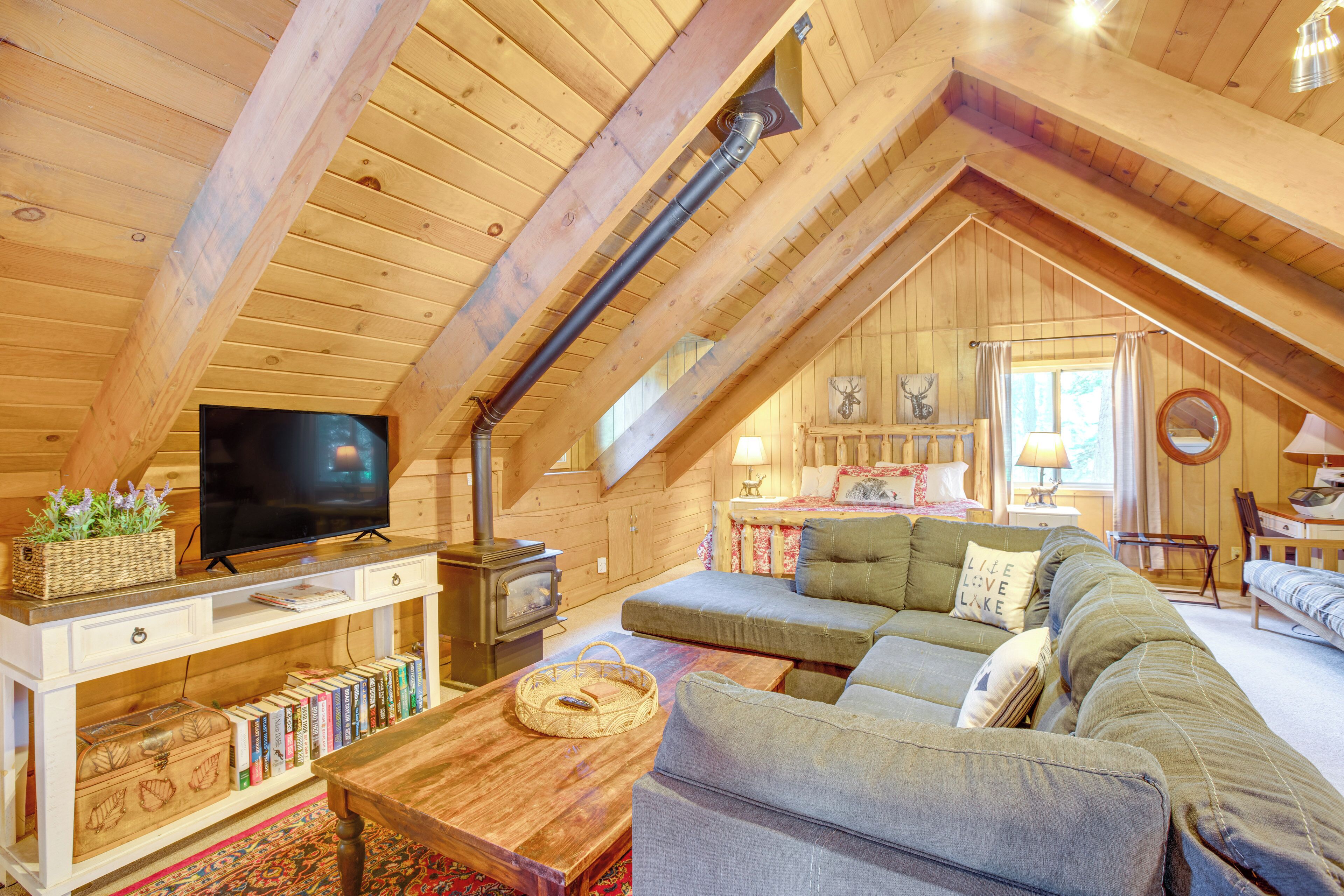 Un accogliente sottotetto con TV, libri, divano e camino.