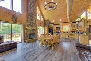 A spacious wooden interior with a large dining table, stone fireplace, and a stone wall. - Stunning North Rose Retreat w/ Fishing Pond! (North Rose)