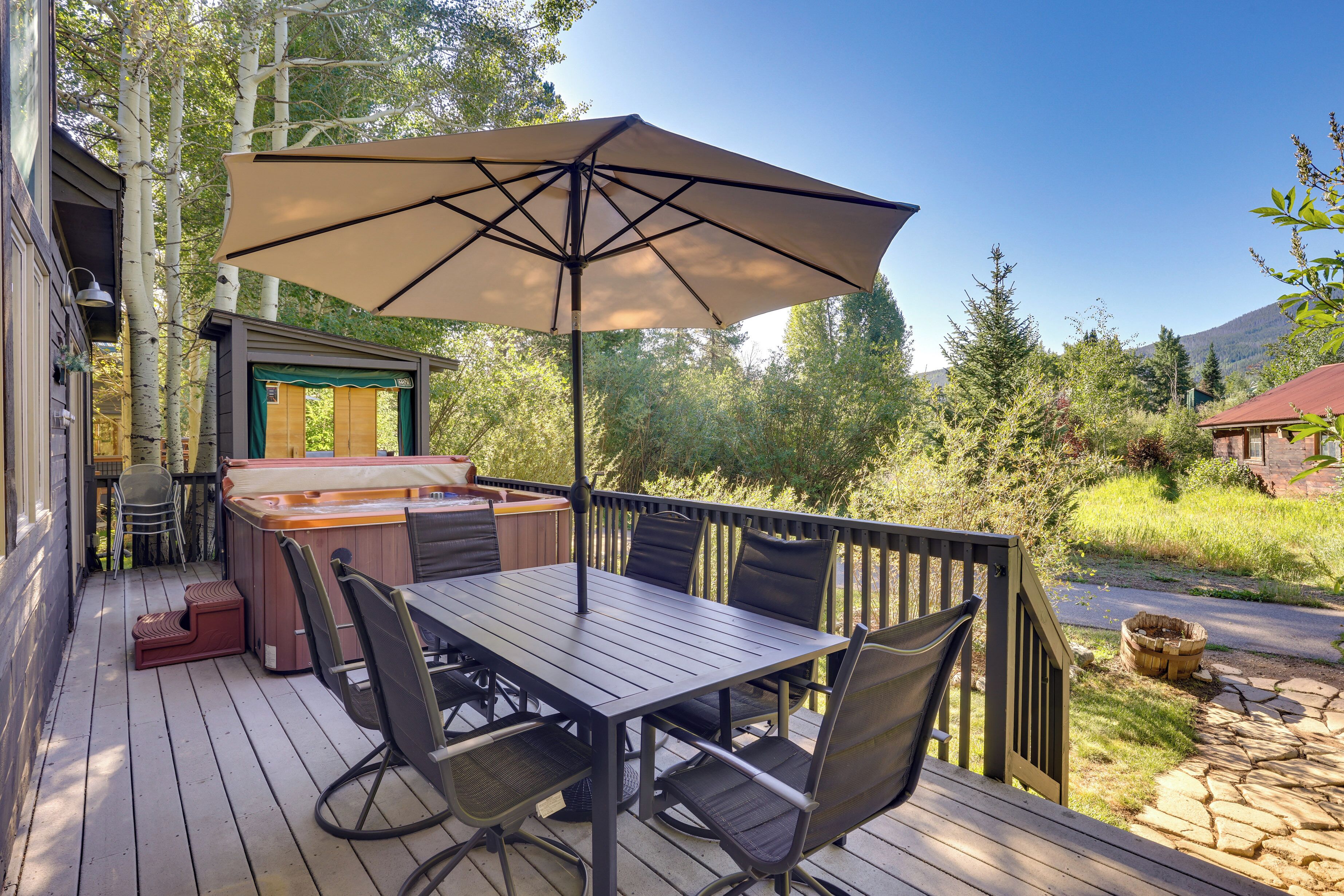 A wooden deck with a hot tub, outdoor seating, and a large umbrella.