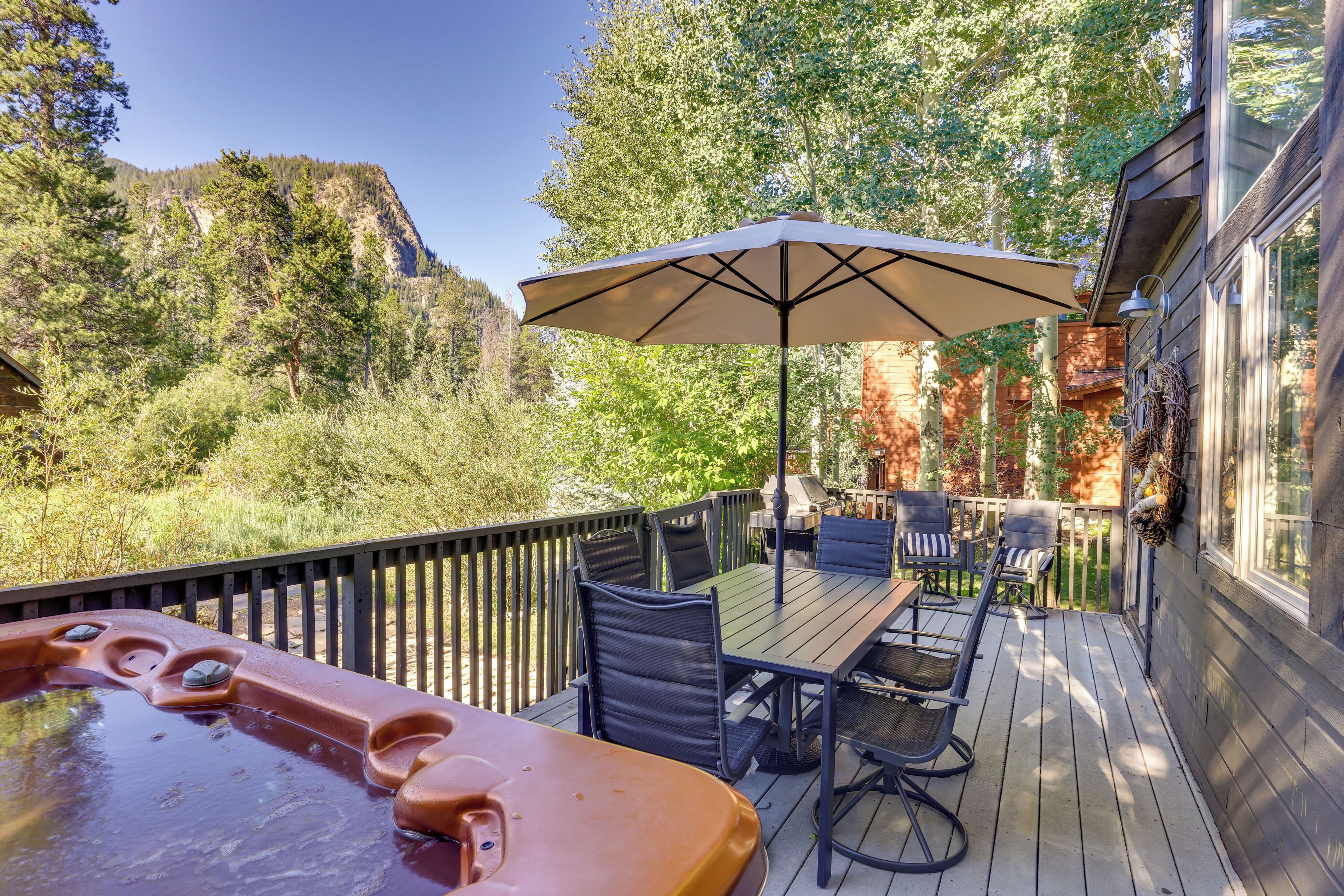 A wooden deck with a hot tub, outdoor seating, and a large umbrella.