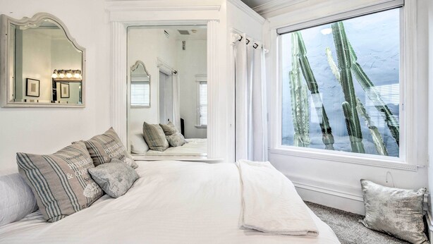 Quarto com uma cama grande, um espelho e uma janela com vista para cactos.