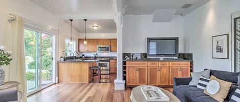 A spacious living area with a dark gray sofa, a wooden coffee table, and a kitchen in the background.