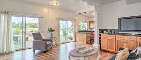 A spacious living room with a sofa, a coffee table, and a television. There is a sliding glass door leading to a patio area.