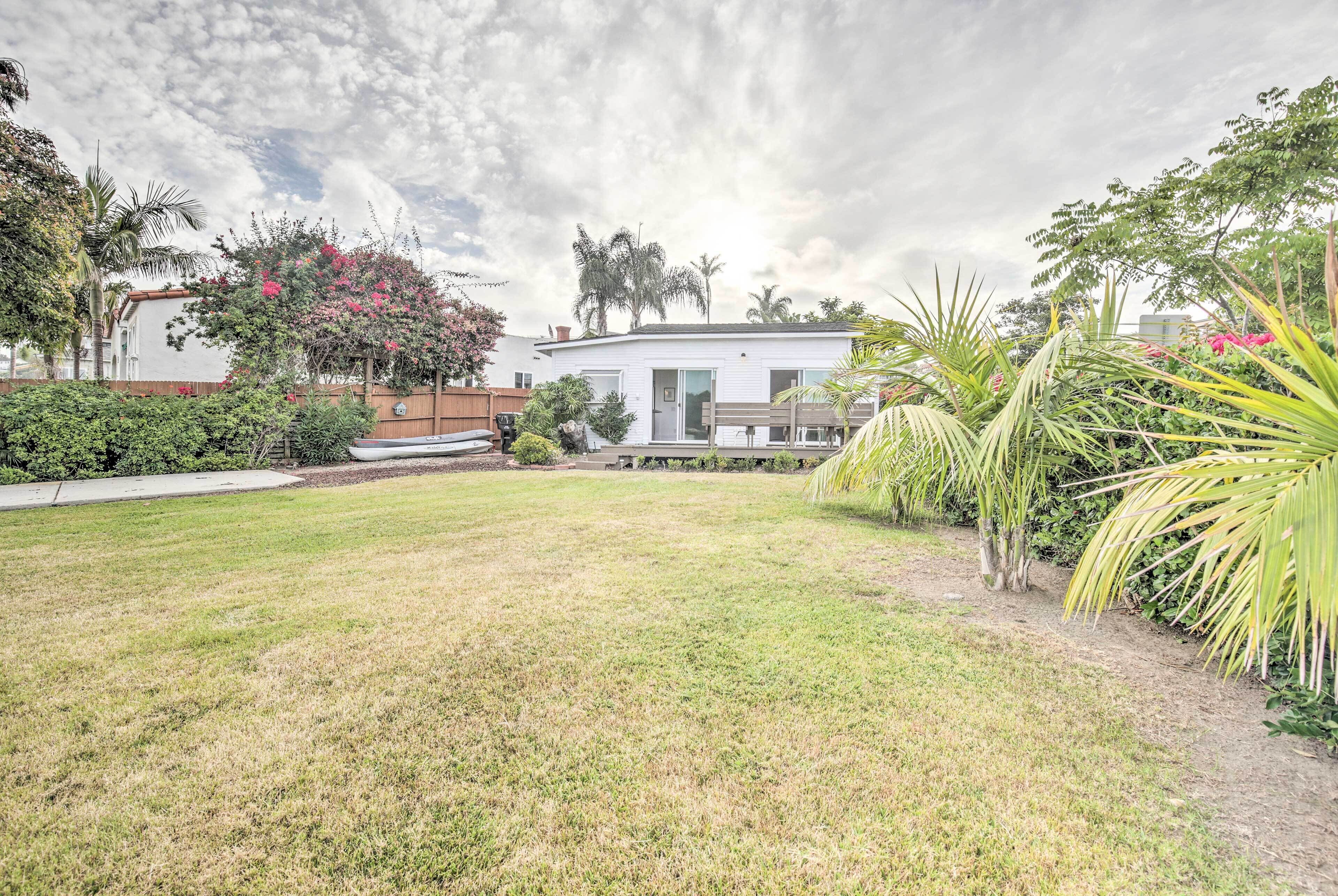 Una casa moderna con un césped cuidado, rodeada de diversas plantas y árboles.