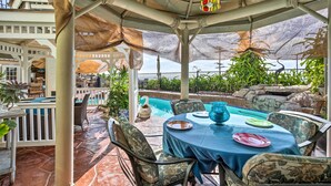 Un patio al aire libre con piscina, mesa y sillas para comer.